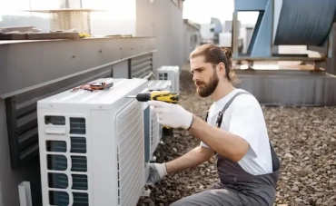 Homme réparant un climatiseur avec une perceuse.