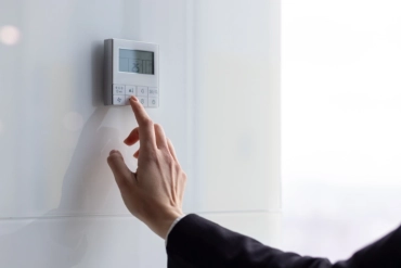 pilotage climatisation Professionnelle et Génie Climatique Pertuis Main ajustant un thermostat moderne.