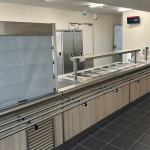 Cantine scolaire vide avec comptoirs en inox.